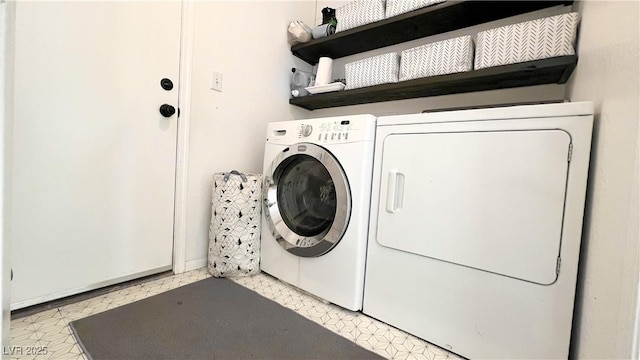 clothes washing area with laundry area, light floors, and separate washer and dryer