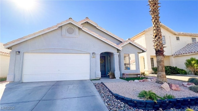 view of front of house with a garage, stucco siding, driveway, and a tile roof