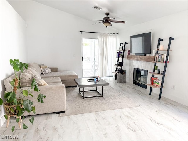 living area with visible vents, a ceiling fan, marble finish floor, and a fireplace