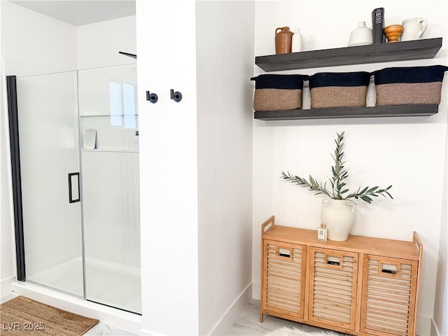 full bath with baseboards, marble finish floor, and a shower stall