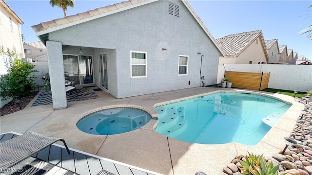 view of swimming pool with a pool with connected hot tub, fence, and a patio area