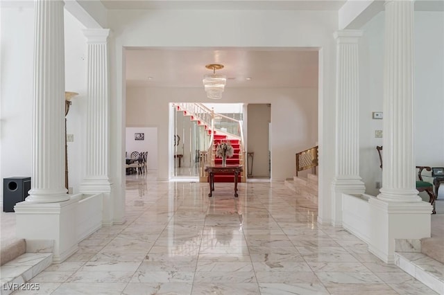 hallway featuring stairs, decorative columns, and marble finish floor