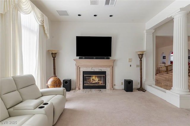 living area with ornate columns, carpet, visible vents, and a premium fireplace