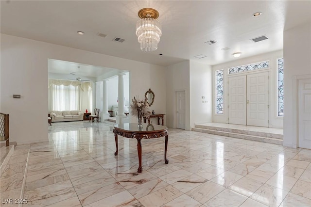 foyer entrance featuring visible vents, marble finish floor, and a chandelier