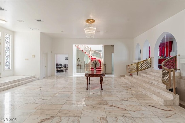 hallway with an inviting chandelier, visible vents, stairs, and marble finish floor
