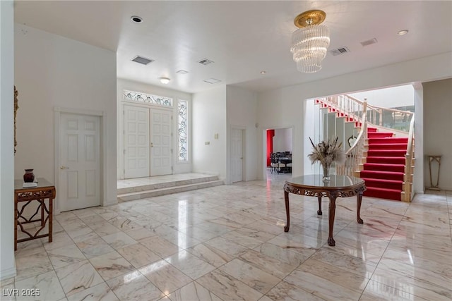 foyer featuring stairway, marble finish floor, a chandelier, and visible vents