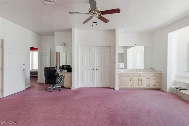 office with a ceiling fan, a textured ceiling, visible vents, a sink, and light carpet