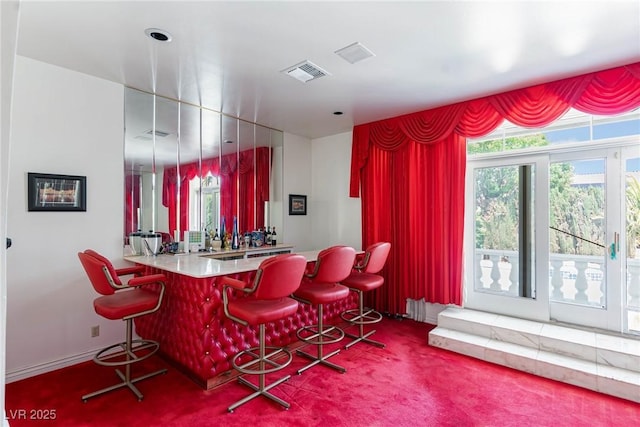 bar with visible vents, carpet, and wet bar