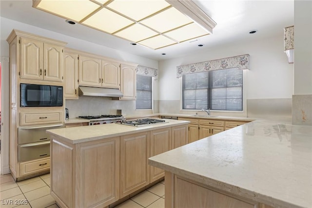 kitchen featuring a warming drawer, black microwave, and light brown cabinets