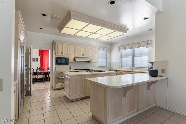 kitchen featuring black microwave, light countertops, a peninsula, light tile patterned floors, and visible vents
