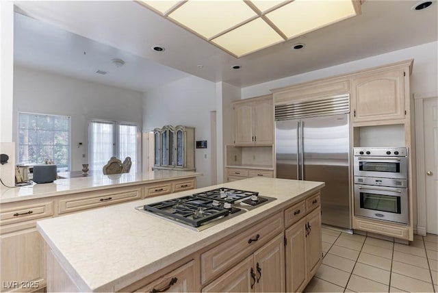 kitchen with light tile patterned floors, light brown cabinetry, a center island, and stainless steel appliances