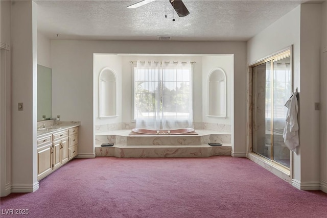 bathroom with a healthy amount of sunlight, a ceiling fan, carpet flooring, and a textured ceiling
