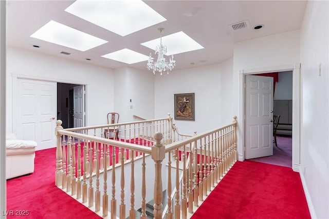 hall featuring carpet floors, a skylight, visible vents, and an upstairs landing