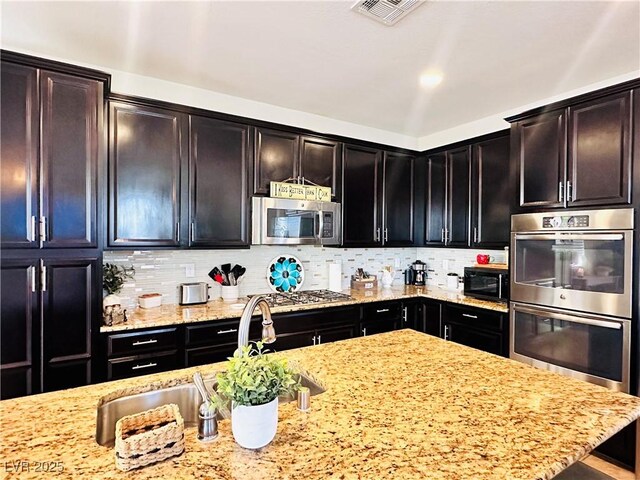 5634 Bishop Flowers St, Las Vegas, NV 89130 - kitchen with stainless steel appliances, light stone countertops, decorative backsplash, and a sink