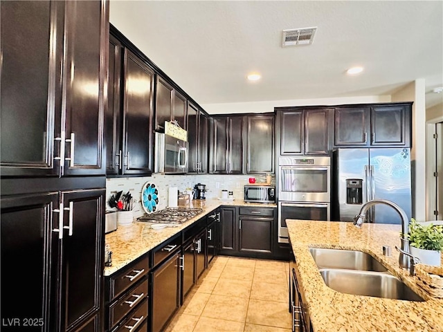 5634 Bishop Flowers St, Las Vegas, NV 89130 - kitchen featuring a sink, stainless steel appliances, light stone counters, light tile patterned floors, and tasteful backsplash