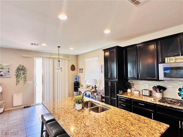 5634 Bishop Flowers St, Las Vegas, NV 89130 - kitchen with appliances with stainless steel finishes, dark cabinetry, a sink, a kitchen breakfast bar, and an island with sink