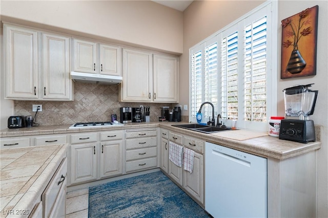 kitchen featuring a sink, white appliances, tile counters, tasteful backsplash, and under cabinet range hood