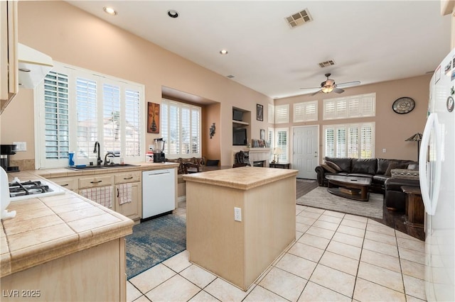 kitchen with ceiling fan, a sink, white appliances, tile counters, and visible vents