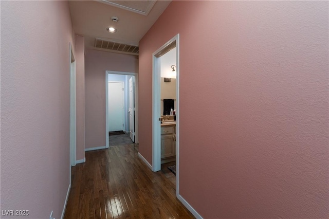 hallway with visible vents, baseboards, dark wood-style floors, recessed lighting, and a sink