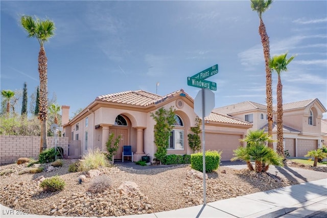 mediterranean / spanish-style home featuring a tile roof, fence, concrete driveway, an attached garage, and stucco siding
