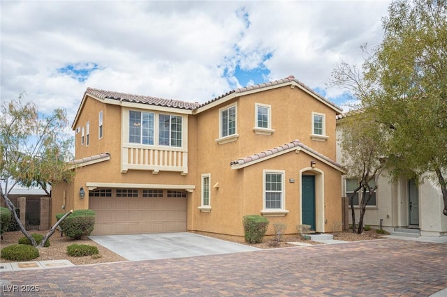 mediterranean / spanish home featuring a tiled roof, stucco siding, concrete driveway, and a garage