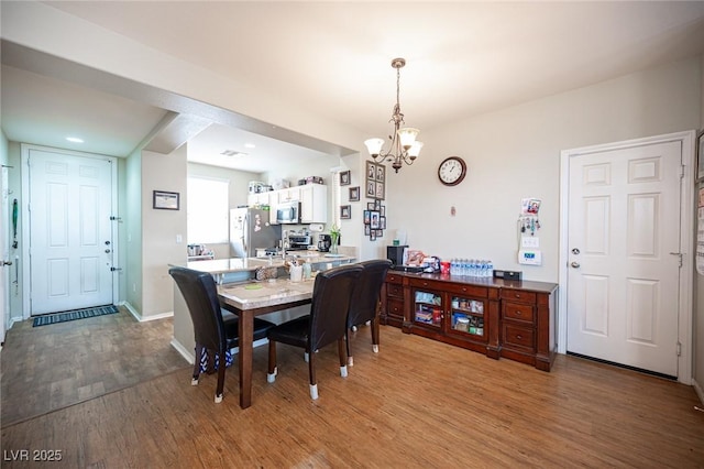 dining space featuring an inviting chandelier, baseboards, wood finished floors, and visible vents