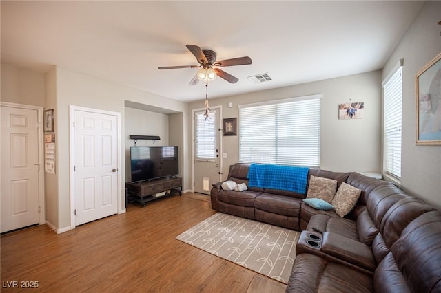 living area with a ceiling fan, visible vents, a healthy amount of sunlight, and wood finished floors