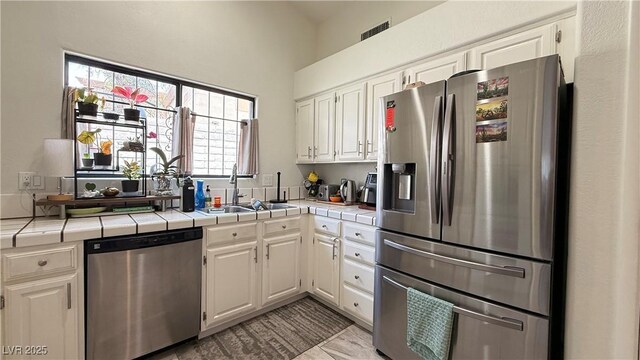 2701 Brookstone Ct, Las Vegas, NV 89117 - kitchen with a sink, white cabinets, stainless steel appliances, and tile countertops