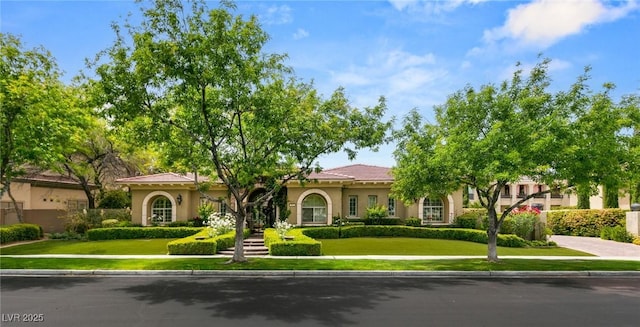 mediterranean / spanish house with stucco siding and a front yard