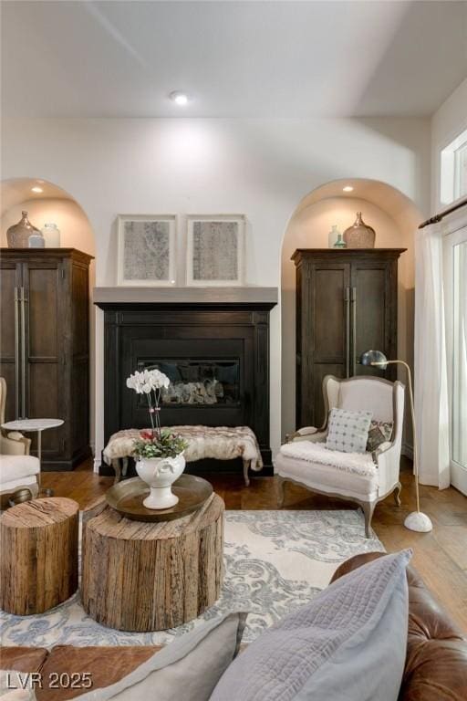 living area with a glass covered fireplace and wood finished floors