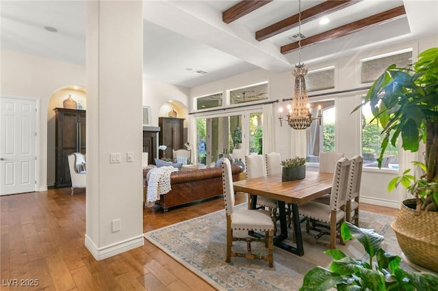 dining area featuring an inviting chandelier, beam ceiling, hardwood / wood-style floors, baseboards, and visible vents