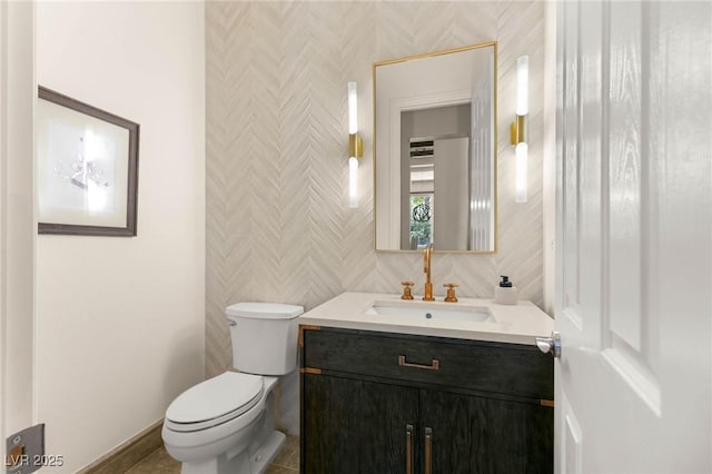 half bathroom featuring vanity, baseboards, and toilet