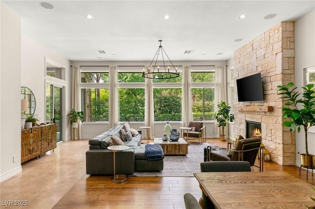 living area with visible vents, an inviting chandelier, a fireplace, baseboards, and recessed lighting