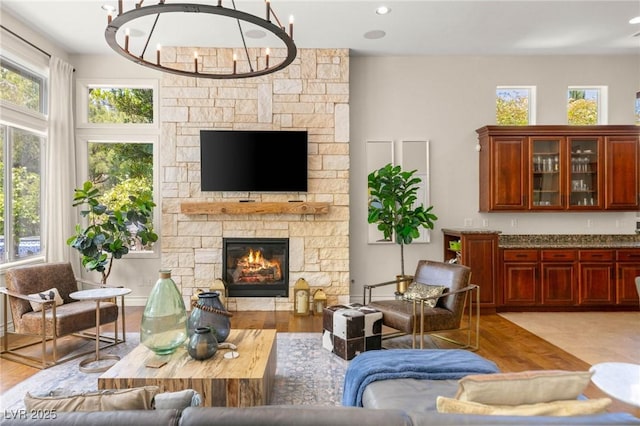 living room with a stone fireplace, recessed lighting, light wood-style flooring, and a chandelier
