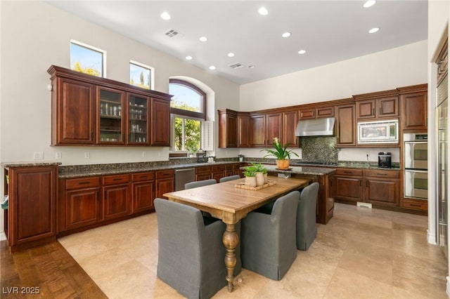 kitchen with visible vents, glass insert cabinets, recessed lighting, under cabinet range hood, and stainless steel appliances