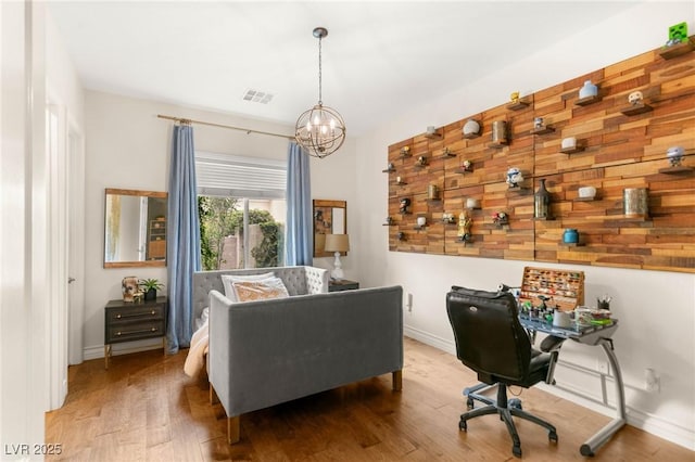 office space featuring a chandelier, baseboards, visible vents, and wood finished floors