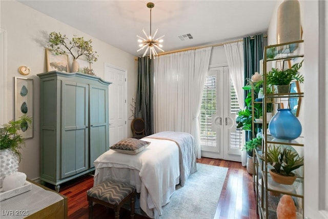 bedroom featuring french doors, visible vents, wood finished floors, a notable chandelier, and access to outside