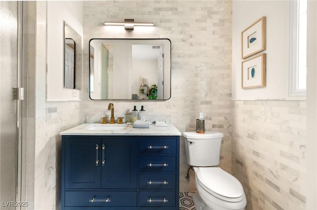 full bath with tile walls, vanity, and toilet