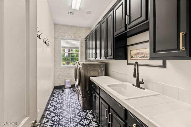 washroom with visible vents, baseboards, washing machine and clothes dryer, a sink, and cabinet space