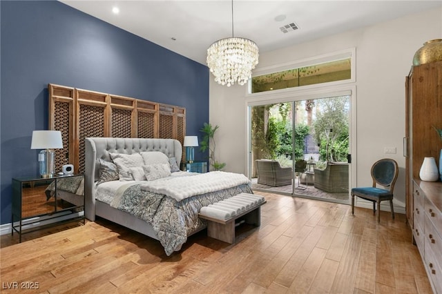 bedroom featuring access to exterior, visible vents, wood finished floors, baseboards, and a chandelier