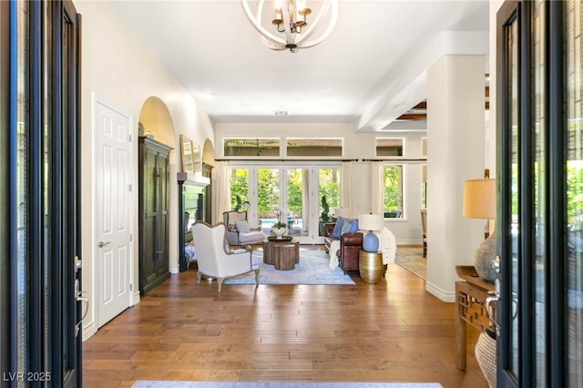 foyer with french doors, arched walkways, baseboards, and hardwood / wood-style floors