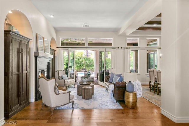 living room with a glass covered fireplace, baseboards, hardwood / wood-style flooring, and visible vents