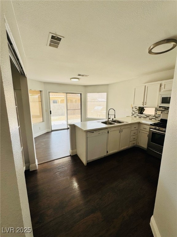5711 Roundrock Dr, Las Vegas, NV 89142 - kitchen with a sink, light countertops, a peninsula, white appliances, and dark wood-type flooring