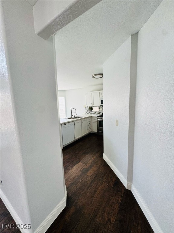 5711 Roundrock Dr, Las Vegas, NV 89142 - corridor featuring baseboards, a sink, and dark wood-type flooring