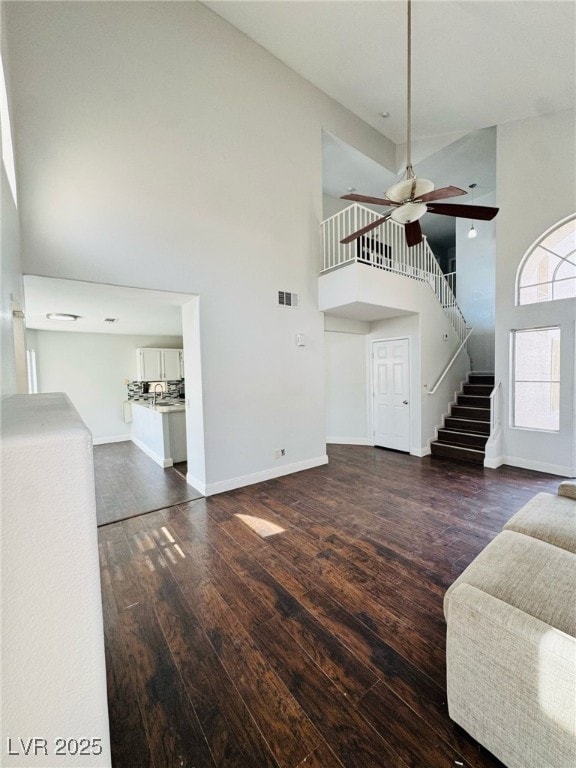5711 Roundrock Dr, Las Vegas, NV 89142 - unfurnished living room with hardwood / wood-style floors, stairs, a ceiling fan, baseboards, and a towering ceiling