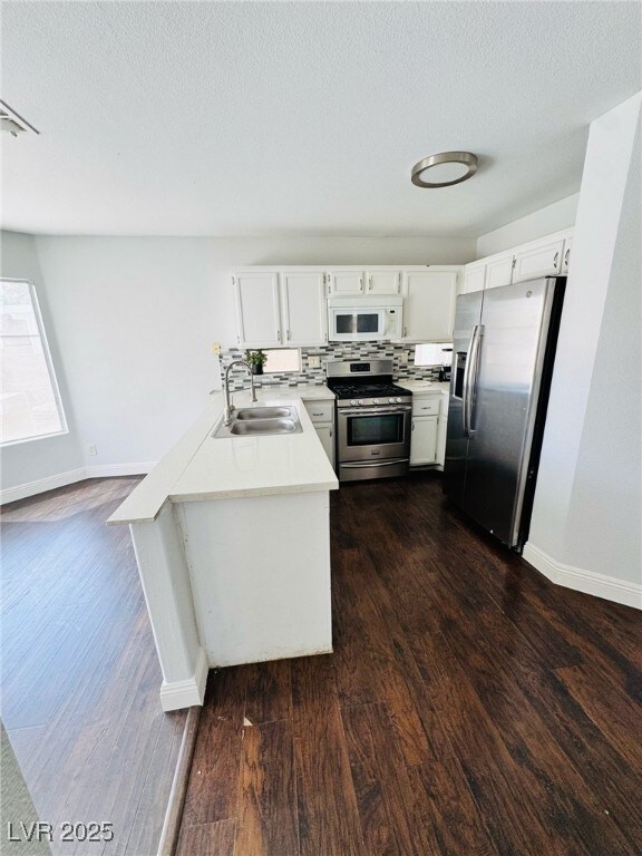 5711 Roundrock Dr, Las Vegas, NV 89142 - kitchen featuring dark wood-style flooring, a sink, light countertops, stainless steel appliances, and baseboards