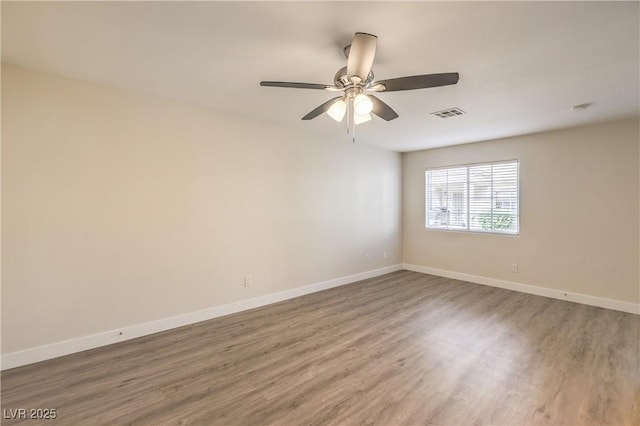 unfurnished room featuring a ceiling fan, baseboards, visible vents, and wood finished floors