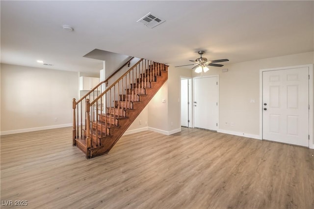 unfurnished living room featuring a ceiling fan, visible vents, baseboards, light wood finished floors, and stairs