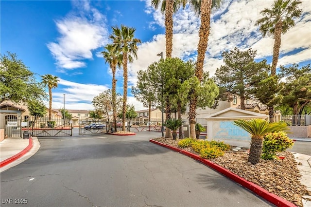 view of street featuring sidewalks, a gated entry, a gate, and curbs