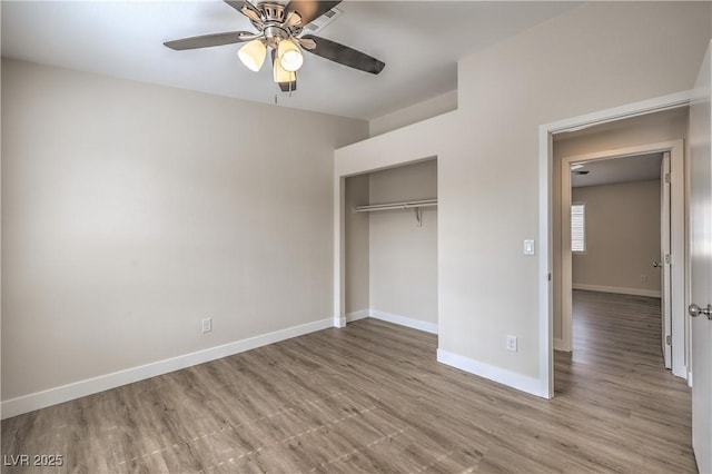 unfurnished bedroom with a ceiling fan, baseboards, wood finished floors, and a closet
